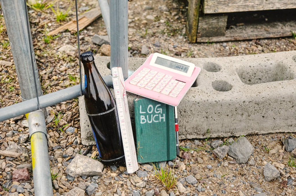 Zollstock, Bierchen, Taschenrechner, Notizbuch mit Aufschrift »LOGBUCH«